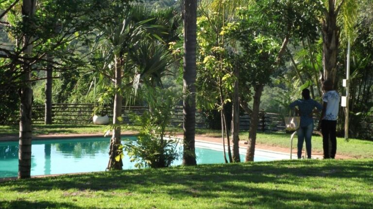 A piscina dos Eagles Nest Chalets no meio do gramado e das árvores, com duas pessoas de pé na borda