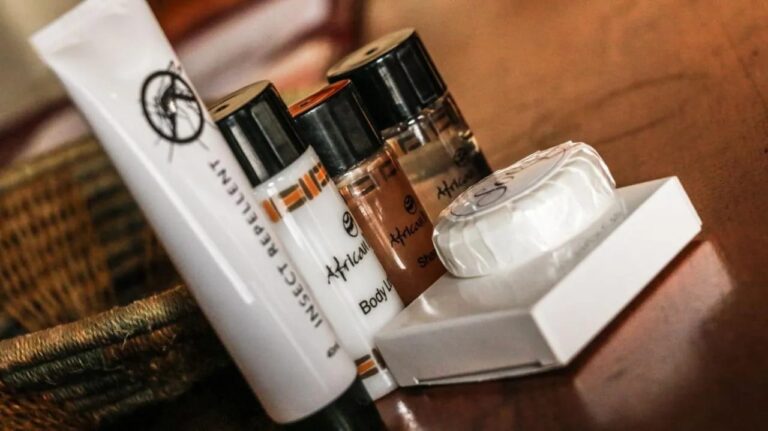 Produtos de cortesia sobre uma mesa de madeira: sabonete, loção corporal e repelente de insetos