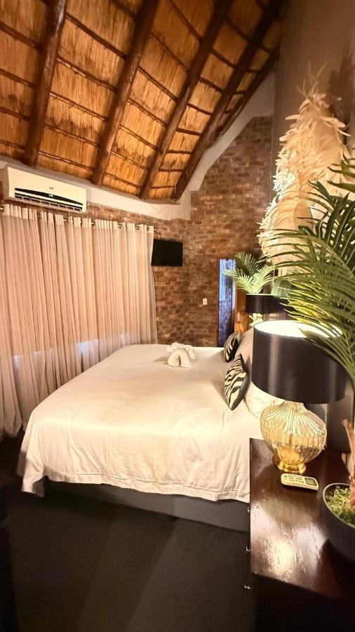 Um quarto sob a palha, com parede de tijolos, ar-condicionado e um abajur de pé dourado