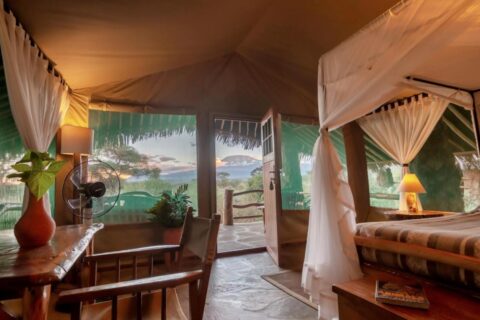 Uma tenda do Kibo Safari Camp aberta para o terraço, com o Kilimanjaro ao longe, ao entardecer