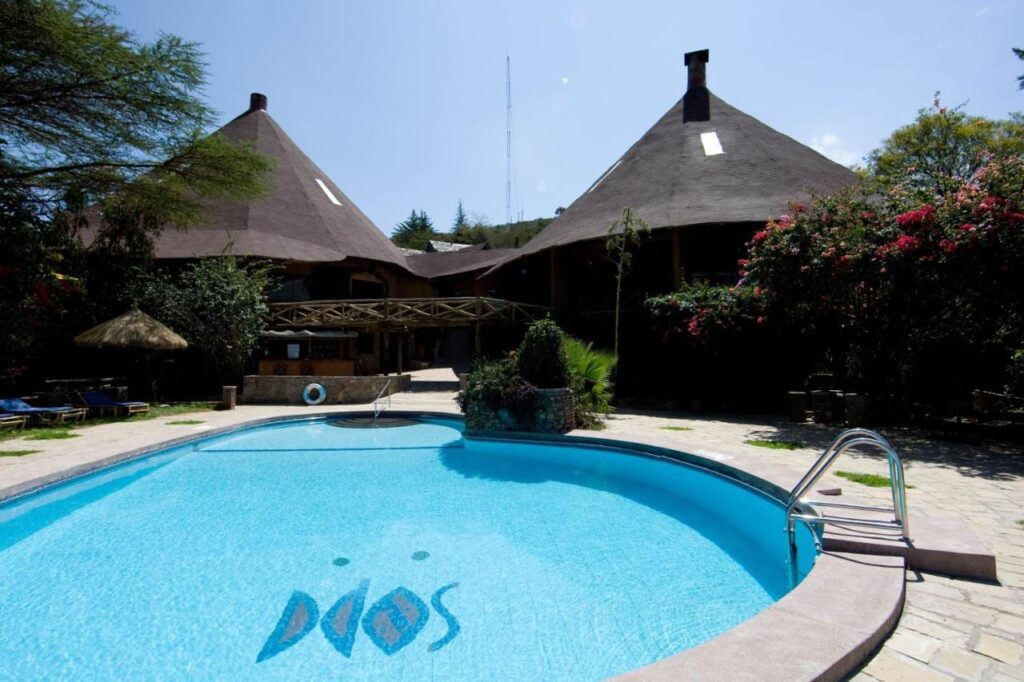 A piscina do Mara Sopa Lodge, diante de prédios com grandes telhados cônicos de palha