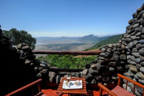 Dois cafés em uma varanda do Ngorongoro Serena Safari Lodge, entre paredes de pedra, acima da cratera