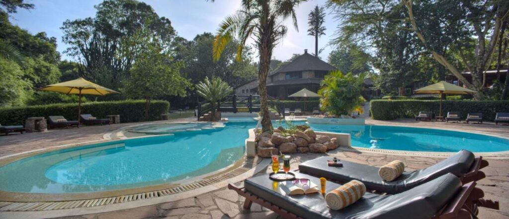 A piscina em forma de lagoa do Sarova Mara Game Camp, em volta de uma ilhota de pedras com uma palmeira