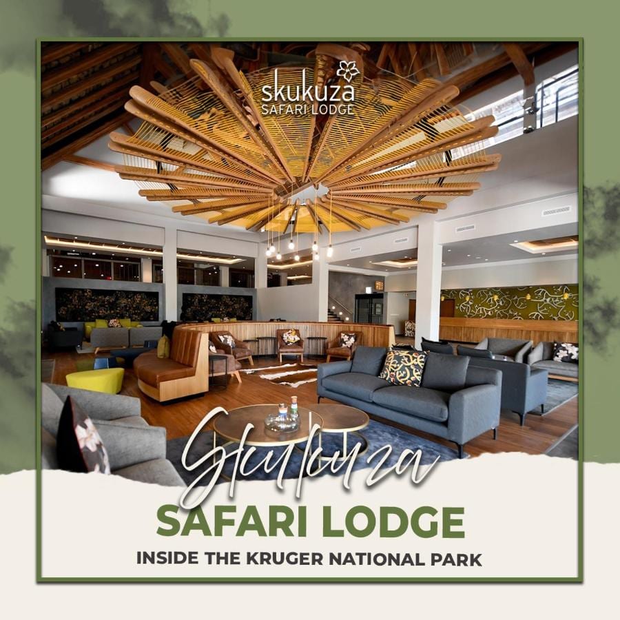A sala de estar do saguão do Skukuza Safari Lodge sob o teto de ripas de madeira em estrela, com o nome do lodge escrito por cima