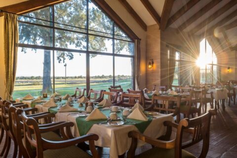 O restaurante do Sweetwaters Serena Camp, com mesas postas diante de uma grande parede de vidro voltada para a planície